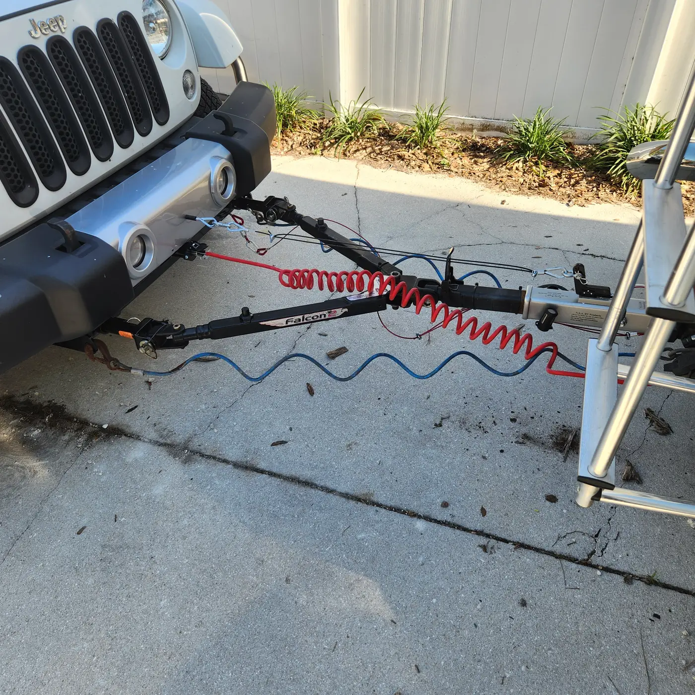 Jeep connected to a flat tow bar with brake and wiring cables in Sarasota, Florida